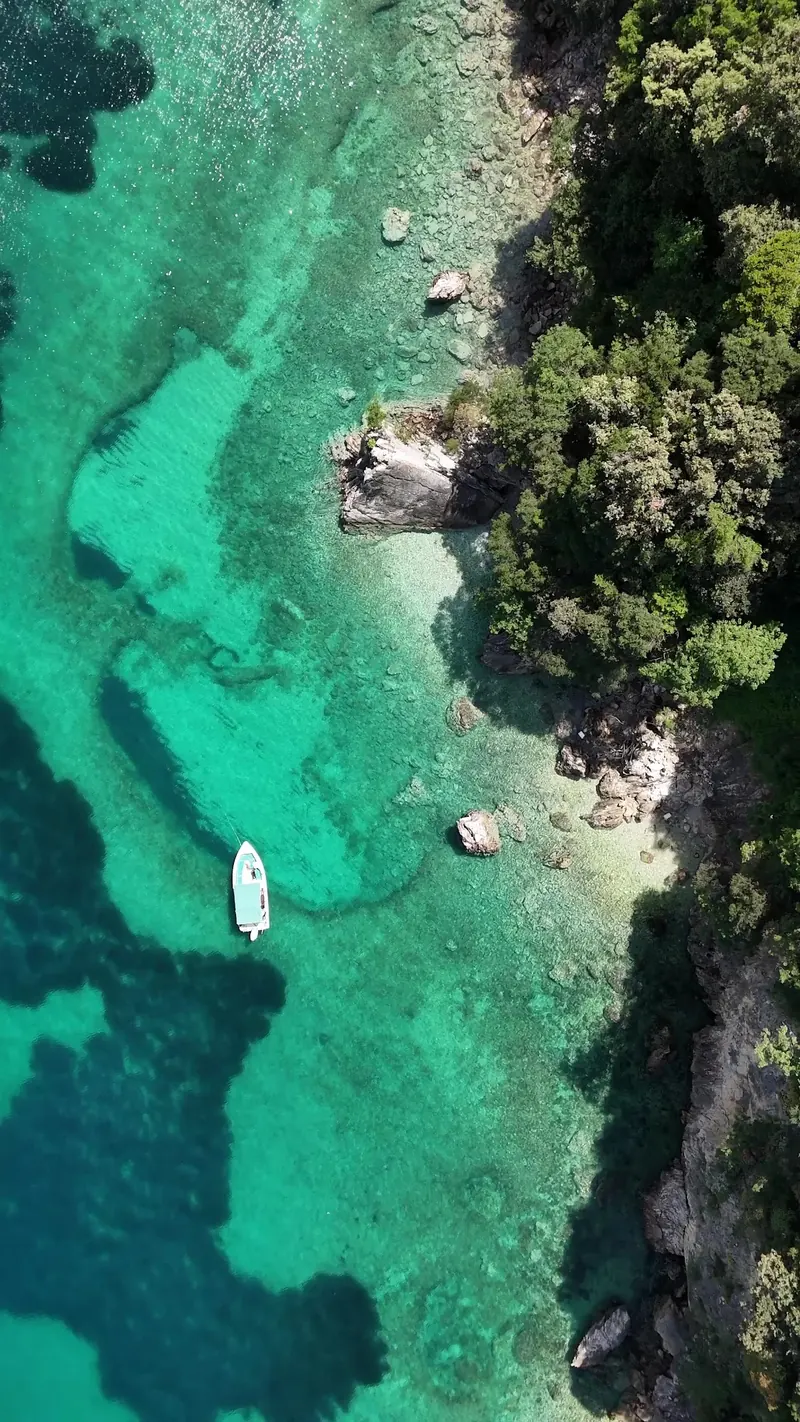 Drone view of a boat anchored over green shallows